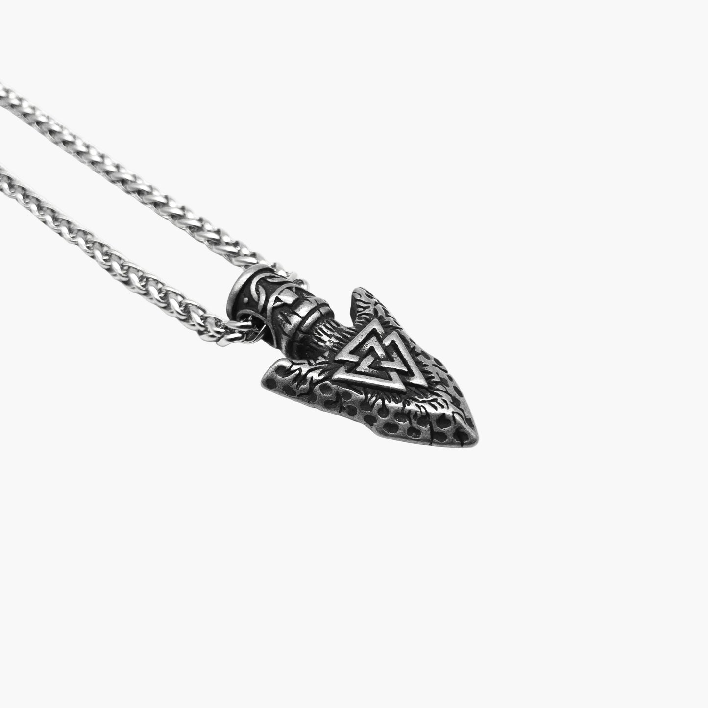left side view of Spearhead Amulet displaying subtle detailing along the silver-colored pendant